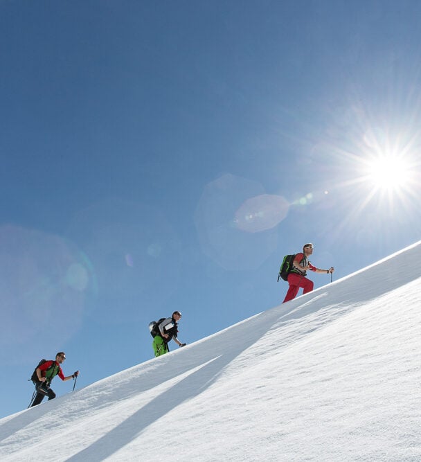 Three backcountry skiers skinning up a slope in Silvretta, Austria.