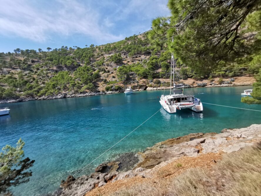 A catamaran ties up to shore on the coast of Croatia.