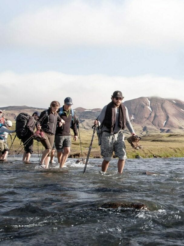 Hikers traversing the river crossing in Iceland.