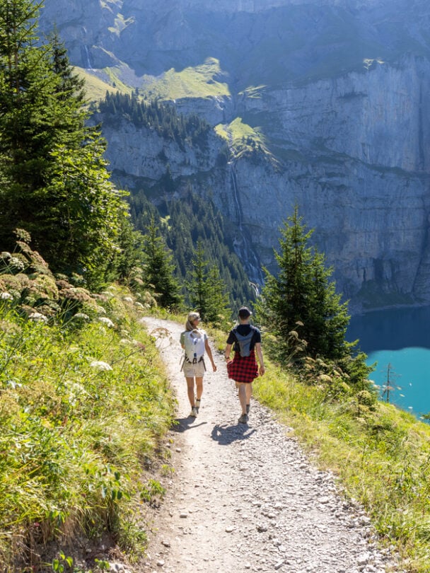 Hikers on a trail beside the Oeschinen lake, Swiss Alps.
